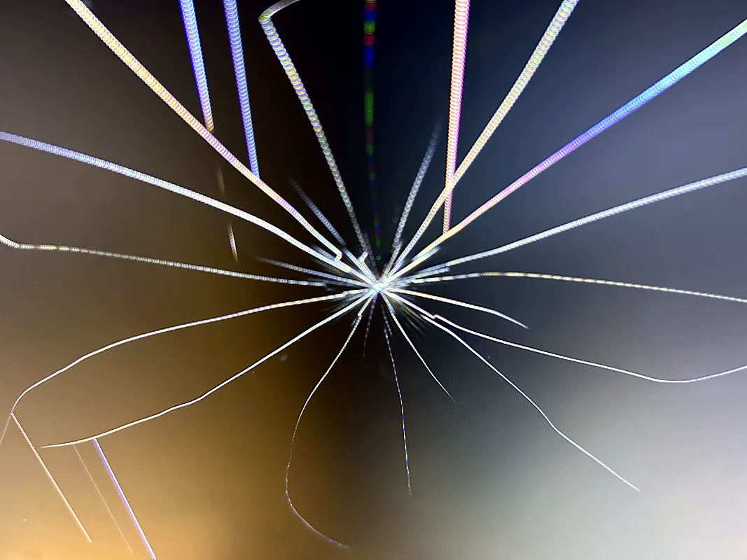 Close-up of a cracked screen with spiderweb fractures spreading from the point of impact
